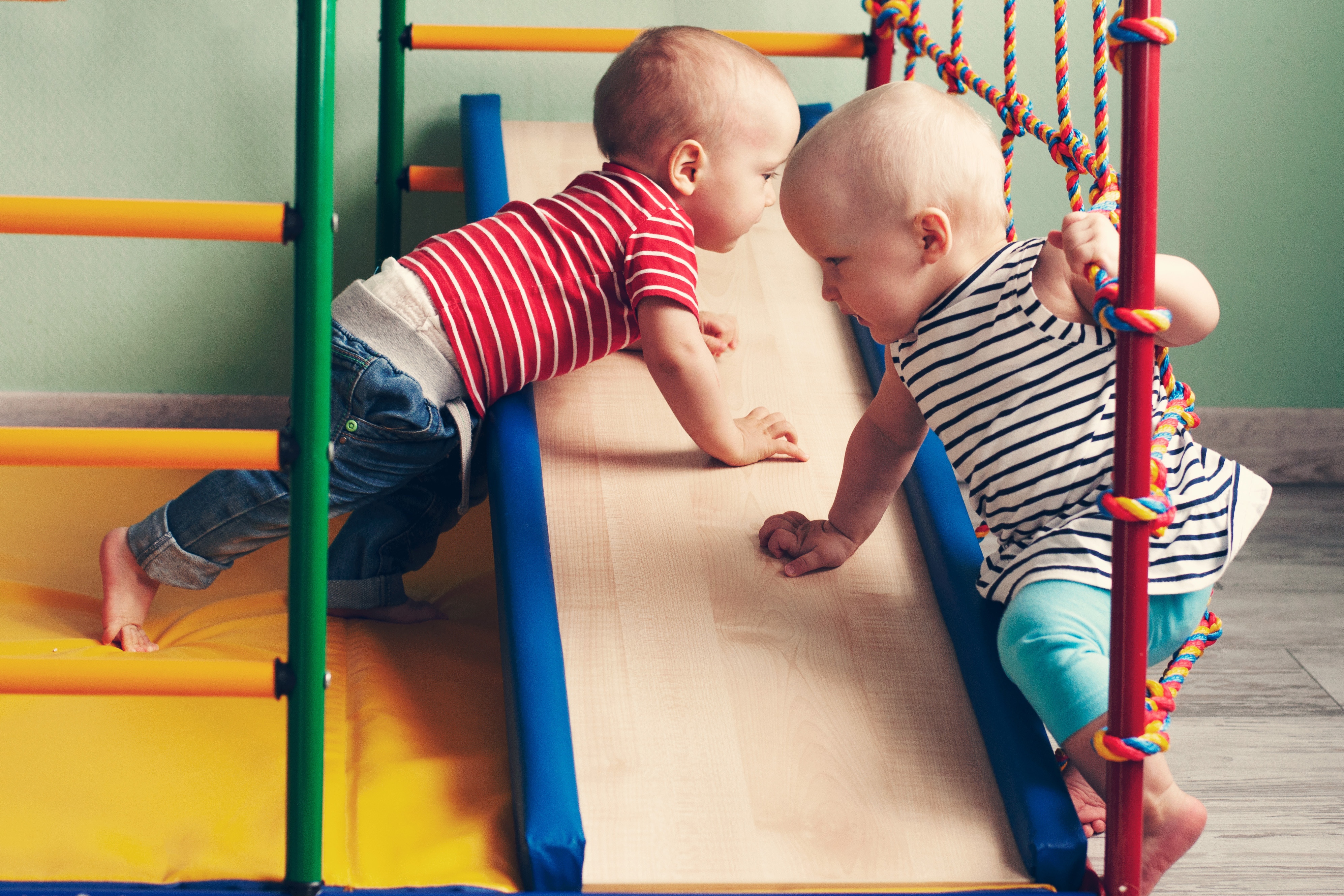 Zwei Babys spielen an einem Turngerät.