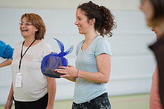 [Translate to Einfache Sprache:] Junge Frau hat einen großen Spielwürfel in der Hand.