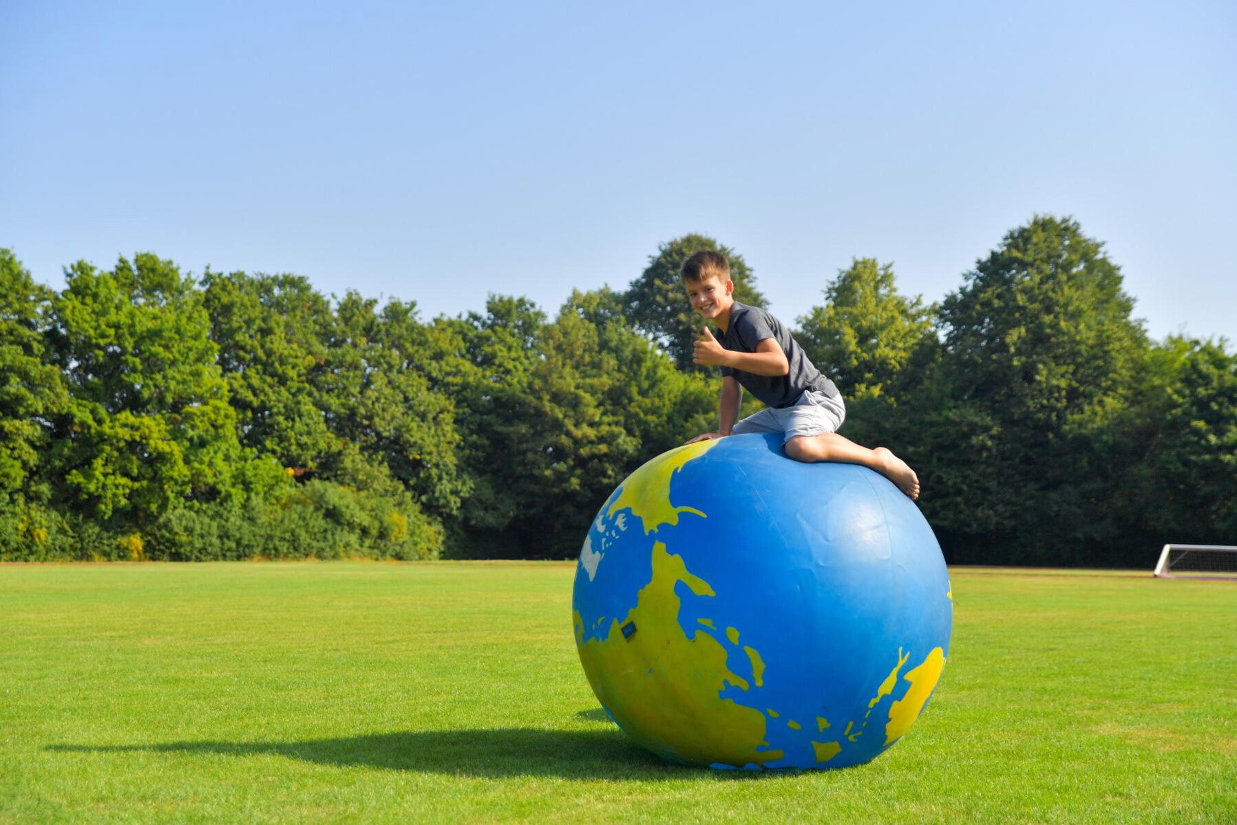 Junge draußen auf großem Ball mit Weltkugel-Optik.