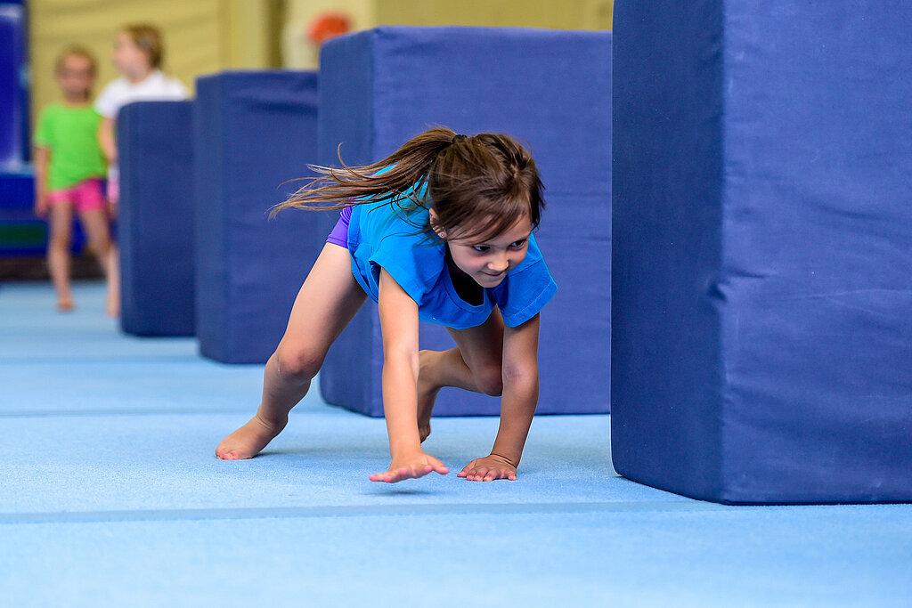 Ein Kind turnt auf einer Matte.