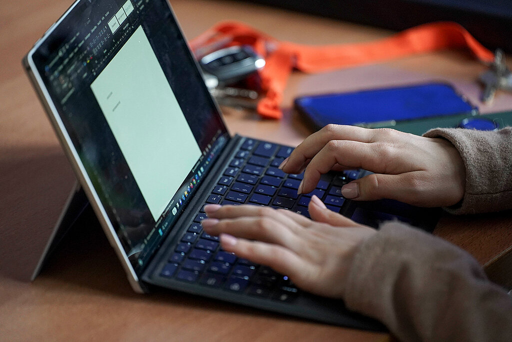 Zwei Hände tippen auf der Tastatur eines Laptops.