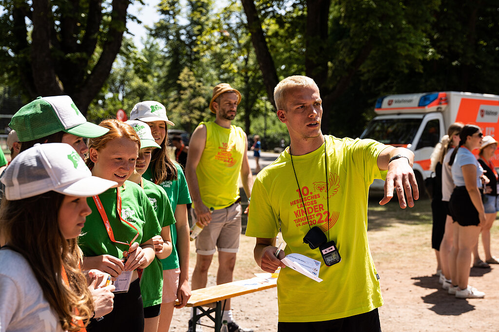 Ein Helfer zeigt Teilnehmenden den Weg.