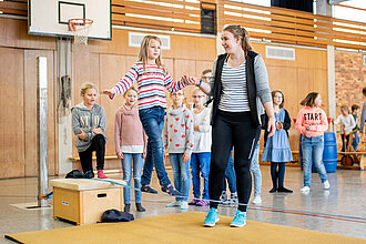 Trainerin mit Kindern in der Halle.