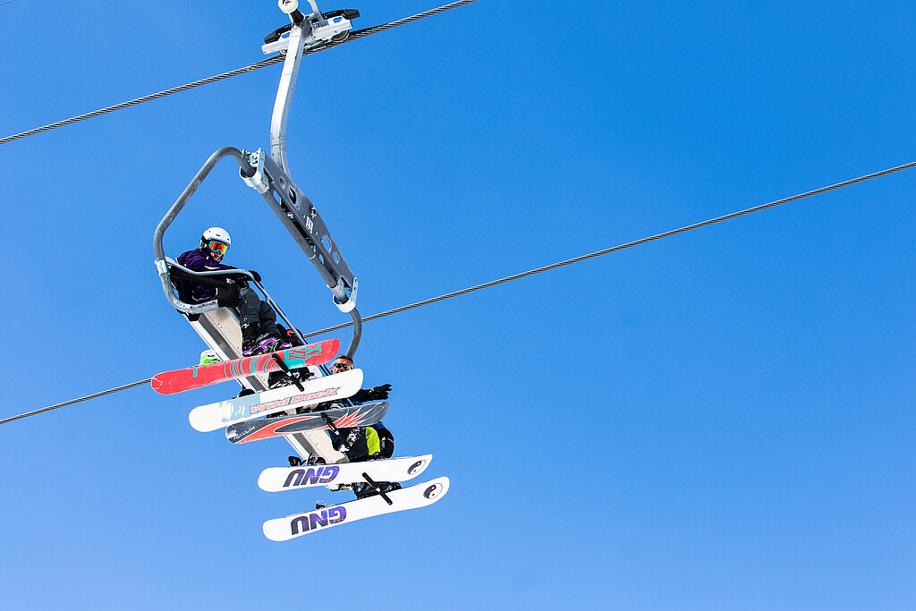 Vier Personen sitzen im Ski-Lift.