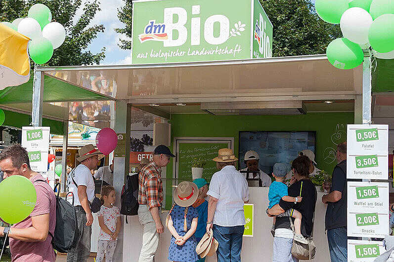 [Translate to Einfache Sprache:] Turnfestteilnehmende holen sich an einem Stand etwas zu essen. 