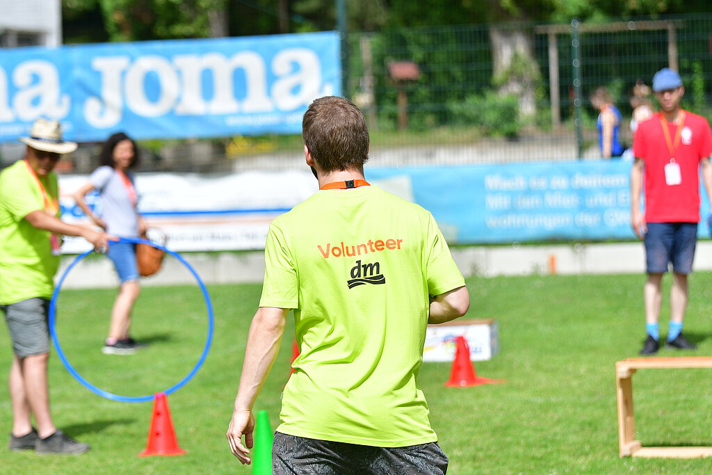 Ein junger Mann von hinten mit der T-Shirt Aufschrift "Volunteer".