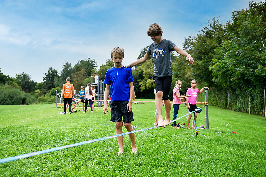 Kinder balancieren auf einer Slack-Line. 