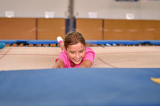 Ein Mädchen rollt über ein großes Trampolin.