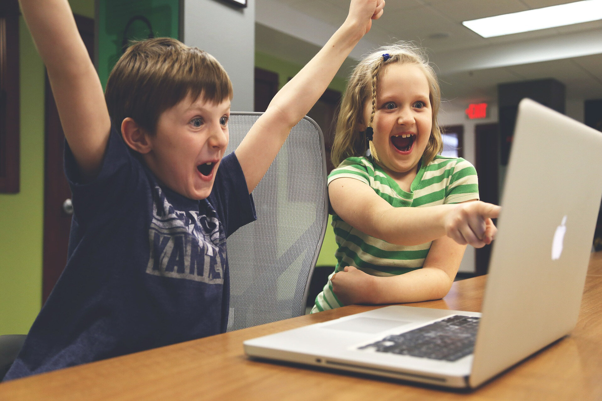 Zwei Kinder freuen sich vor dem Laptop.