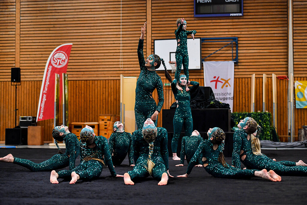 [Translate to Einfache Sprache:] Eine Gruppe in glitzernden Kostümen präsentiert eine Show.