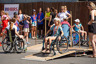 Ein Kind sitzt in einem Rollstuhl und durchquert einen Parkour.