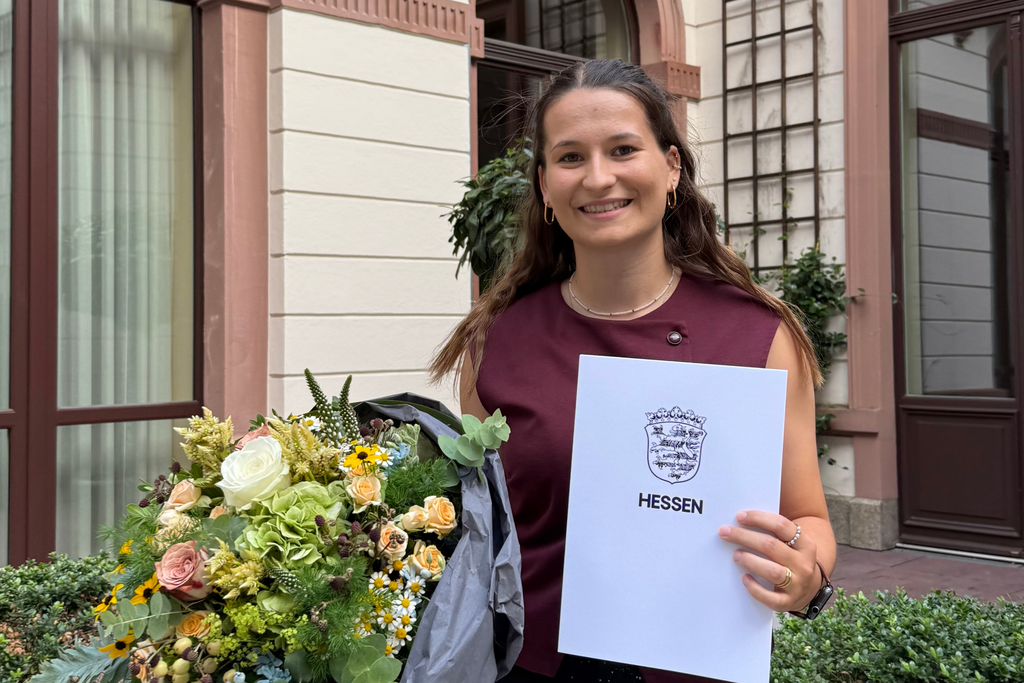 Paula Gremm hält eine Urkunde und einen Blumenstrauß in den Händen.