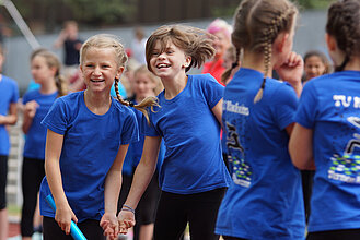 Zwei Mädchen in blauen T-Shirts lachen.