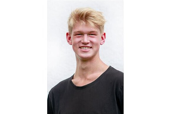 Ein blonder Junge lacht in die Kamera. 