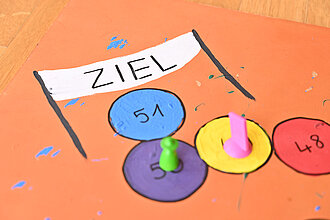 Zwei Hütchen stehen auf einem Spielbrett.