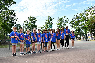 Mehrere Kinden stehen im Turnfest-T-Shirt in einer Reihe aufgestellt auf einem Schulhof.