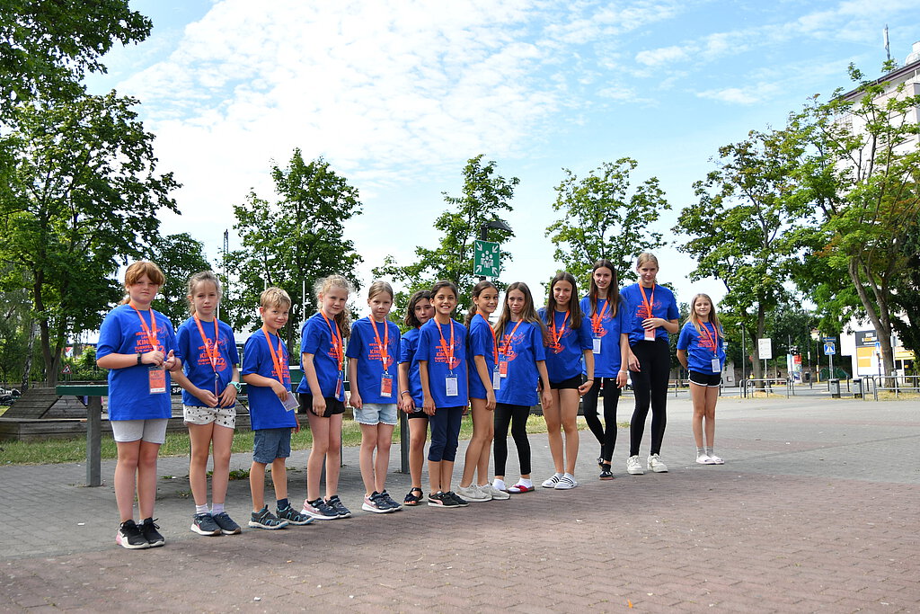 Mehrere Kinden stehen im Turnfest-T-Shirt in einer Reihe aufgestellt auf einem Schulhof.