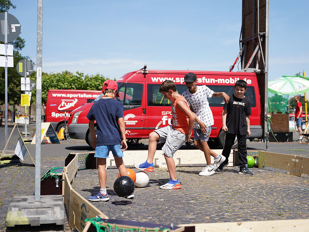 Kinder spielen auf der Straße Fußball.
