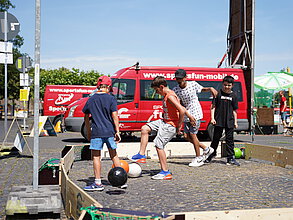 Kinder spielen auf der Straße Fußball.