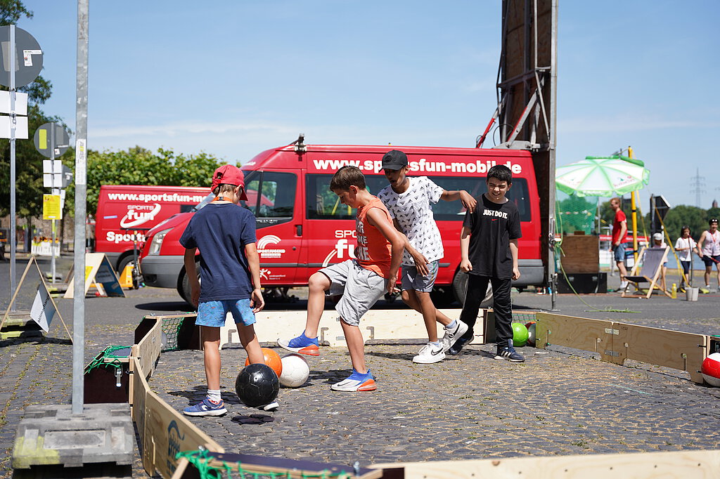 Kinder spielen auf der Straße Fußball.