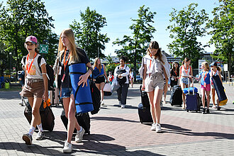 Mehrere Mädchen laufen mit Koffern auf der Straße. 