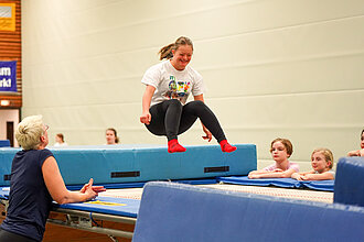 Ein Mädchen mit Behinderung springt auf einem großen Trampolin