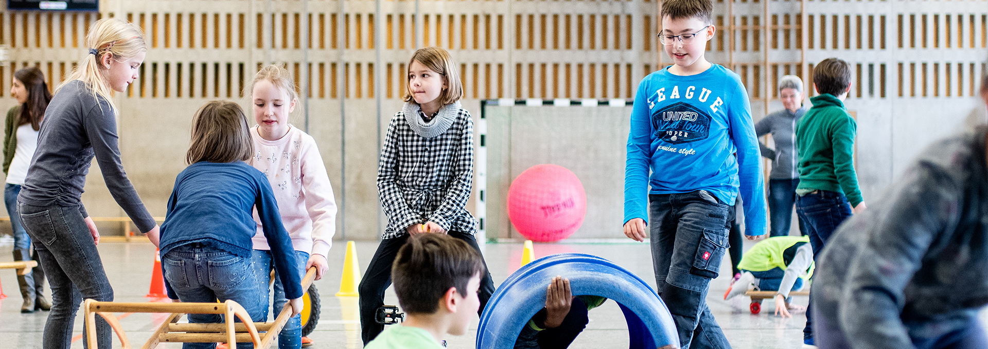 Viele Kinder bewegen sich mit Kleingeräten in der Sporthalle.
