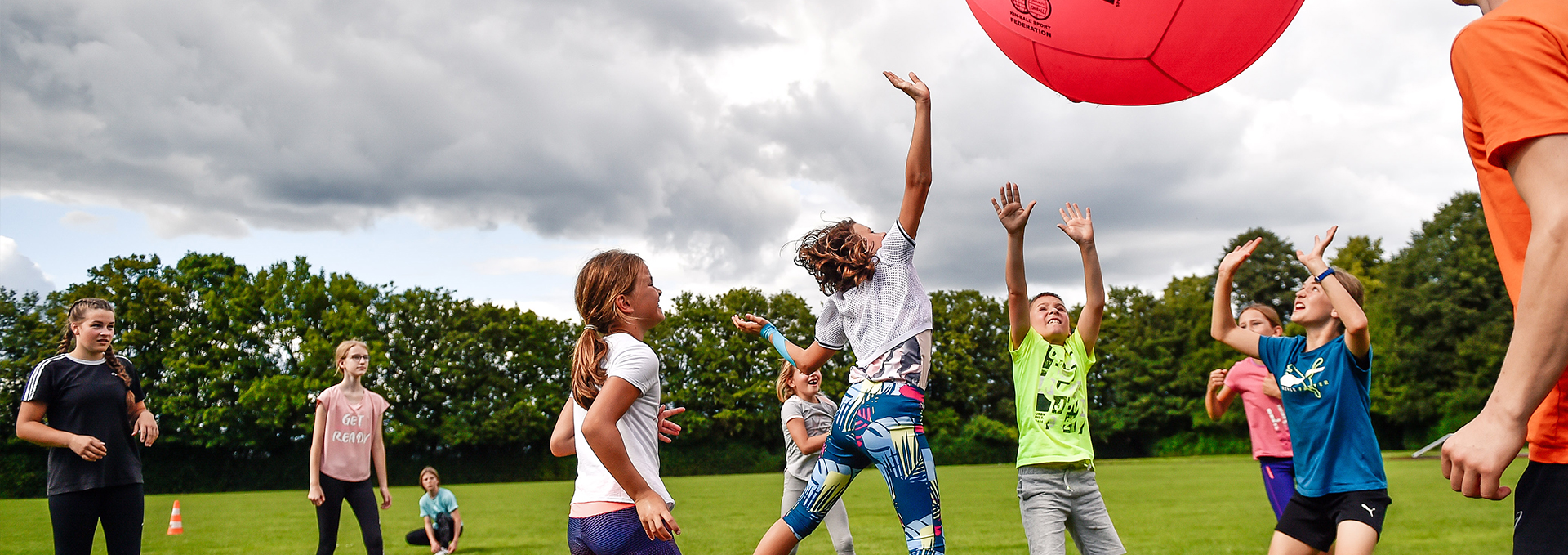 Viele Kinder spielen draußen mit einem großen Fußball.
